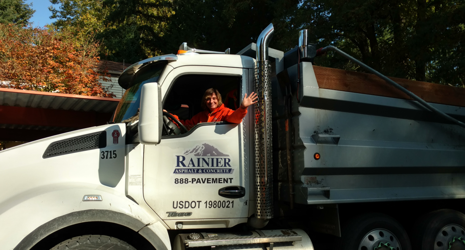 White Rainier construction truck with driver at autumn roadside