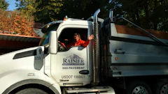 White Rainier construction truck with driver at autumn roadside