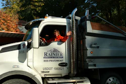 White Rainier construction truck with driver at autumn roadside