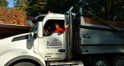 White Rainier construction truck with driver at autumn roadside