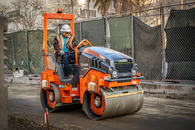 Orange Hamm road roller compacting pavement at construction site