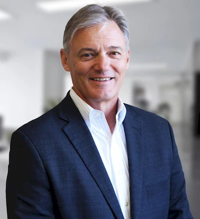 Smiling professional in navy blazer and white shirt in office setting