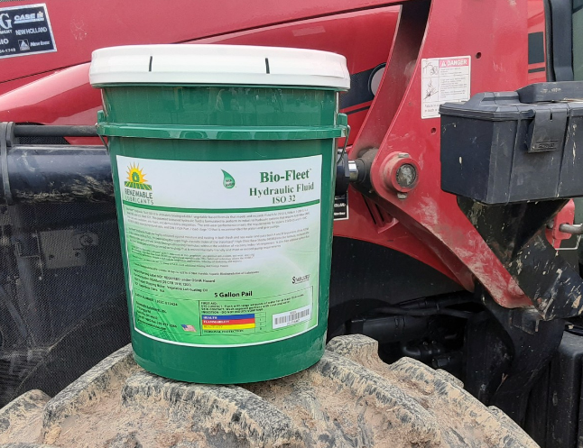 Green Bio-Fleet hydraulic fluid bucket on red machinery near rocky surface