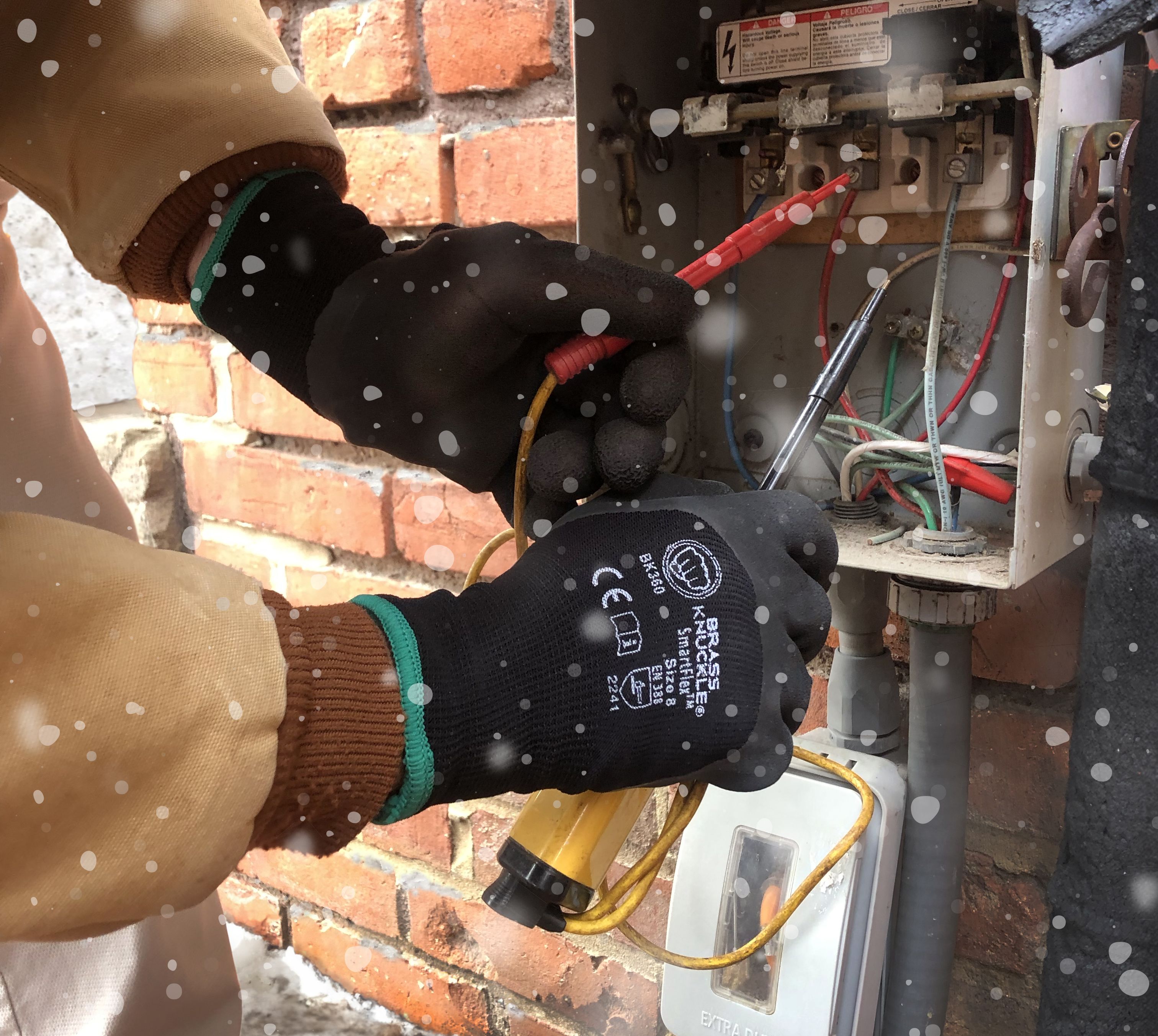 Technician wearing safety gloves repairing electrical panel near brick wall