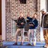 Three construction professionals reviewing plans near brick fireplace during site inspection