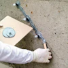 Construction worker's gloved hand drilling into concrete wall