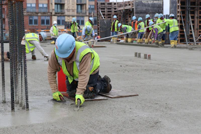 Construction workers in safety gear smoothing concrete at building site
