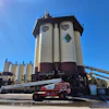KMG industrial facility with large white and maroon storage silos and red telescopic crane