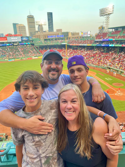 Family of four smiling together at Fenway Park baseball stadium in Boston