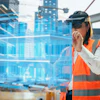 Construction professional using VR headset to interact with blue holographic building model