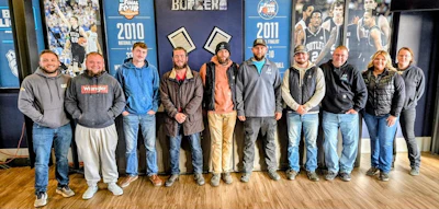 Group of ten people standing together in front of sports team year posters