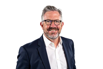 Smiling professional in navy blazer and white shirt wearing glasses