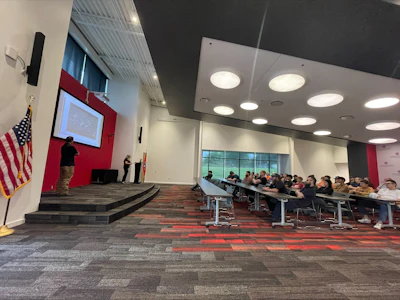 Professional conference room with presenter, screen, and audience seated at desks