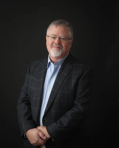 Professional portrait of a mature executive in a dark blazer and blue shirt