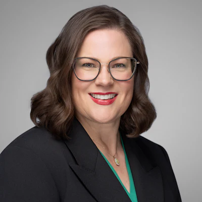 Professional woman in black blazer and glasses smiling confidently