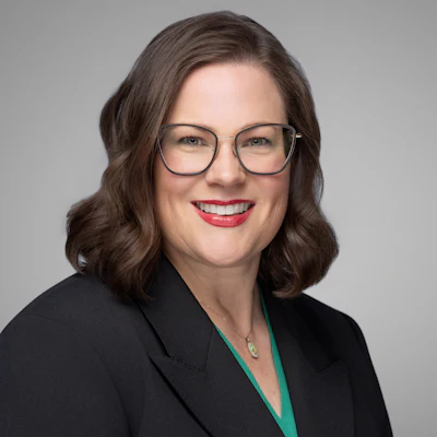Professional woman in black blazer and glasses smiling confidently