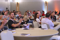 Conference attendees gathered at round tables in a professional meeting space