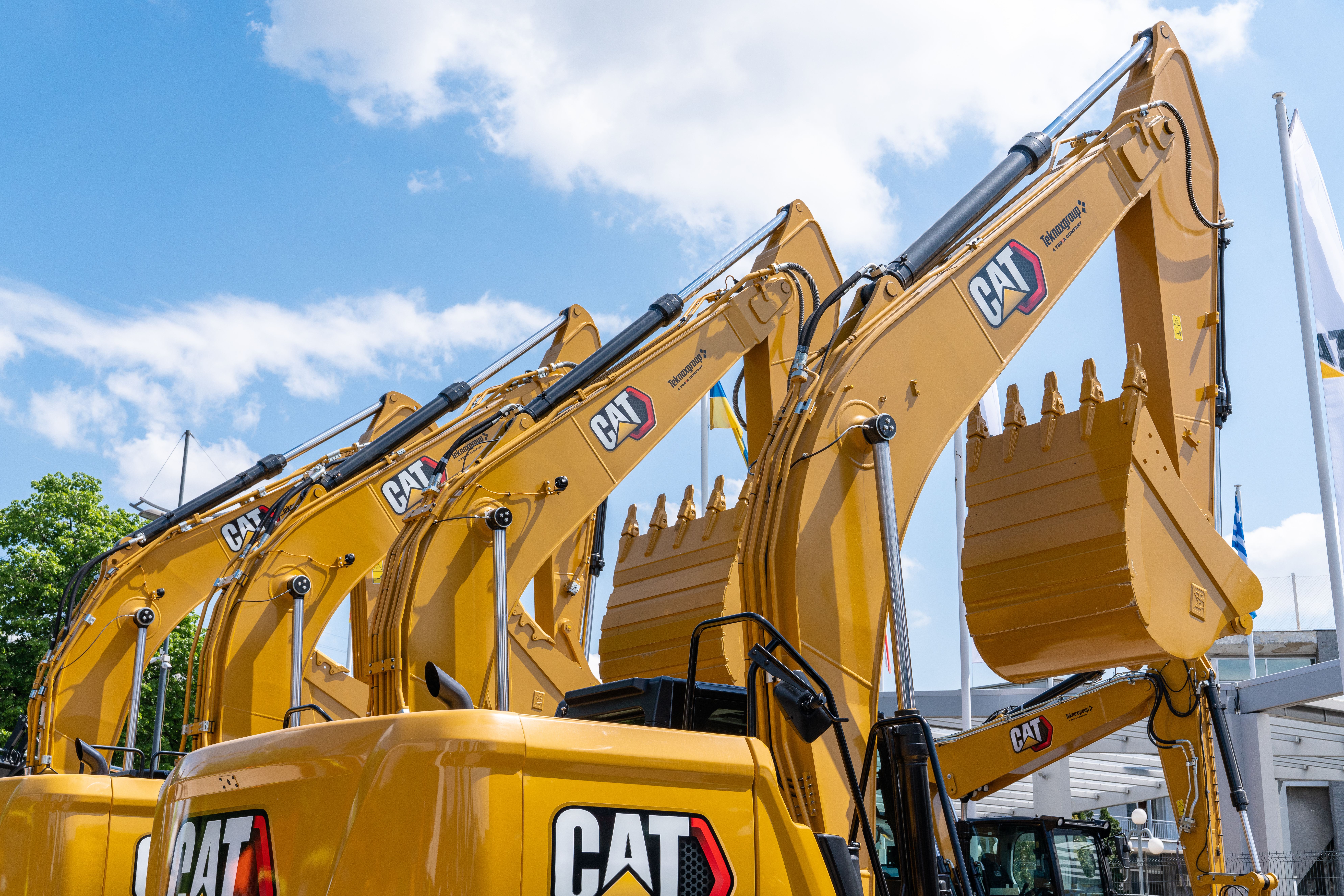 Yellow Caterpillar excavators lined up against blue sky with clouds