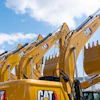 Yellow Caterpillar excavators lined up against blue sky with clouds