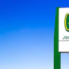 John Deere green and yellow logo sign against bright blue sky