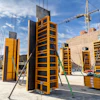 Yellow construction formwork panels and crane at building site with brick walls