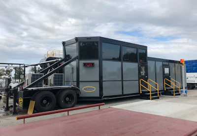 Gray mobile trailer with yellow safety railings on a construction site