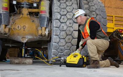 Construction worker using yellow Enerpac hydraulic equipment near industrial machinery