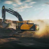 Yellow Hyundai excavator digging in dusty construction site with rocky terrain