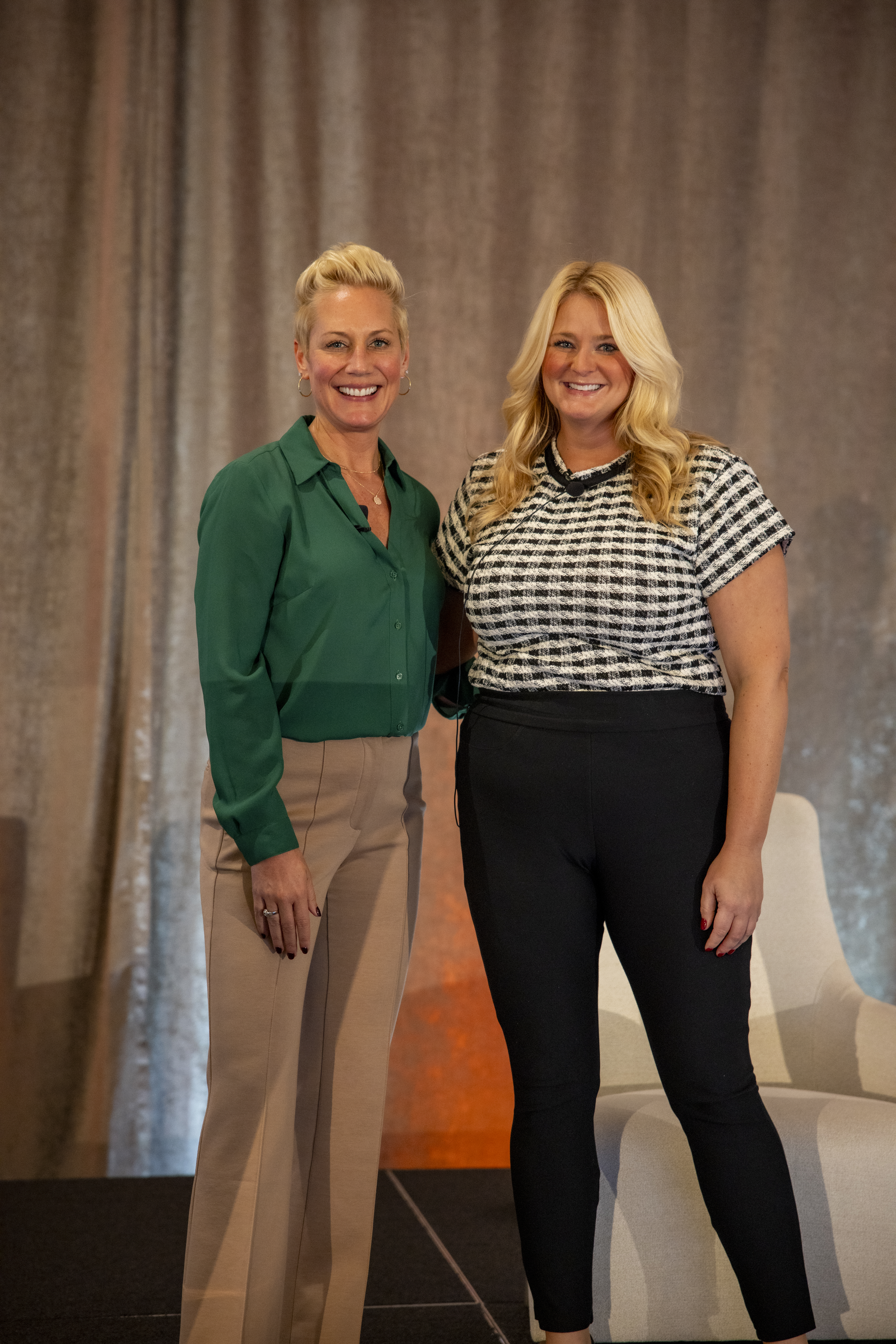 Two smiling blonde women in professional business attire standing together