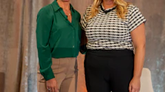 Two smiling blonde women in professional business attire standing together