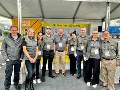 Team of eight professionals in gray uniforms at corporate event marking 40-year milestone