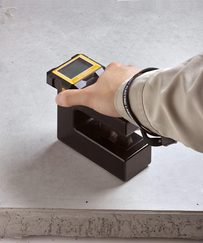 Hand operating a black and yellow digital scanning device on a charging base