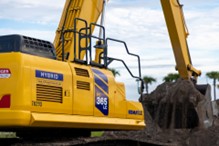 Yellow excavator digging at construction site with cloudy sky