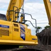 Yellow excavator digging at construction site with cloudy sky