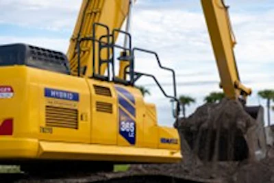 Yellow excavator digging at construction site with cloudy sky