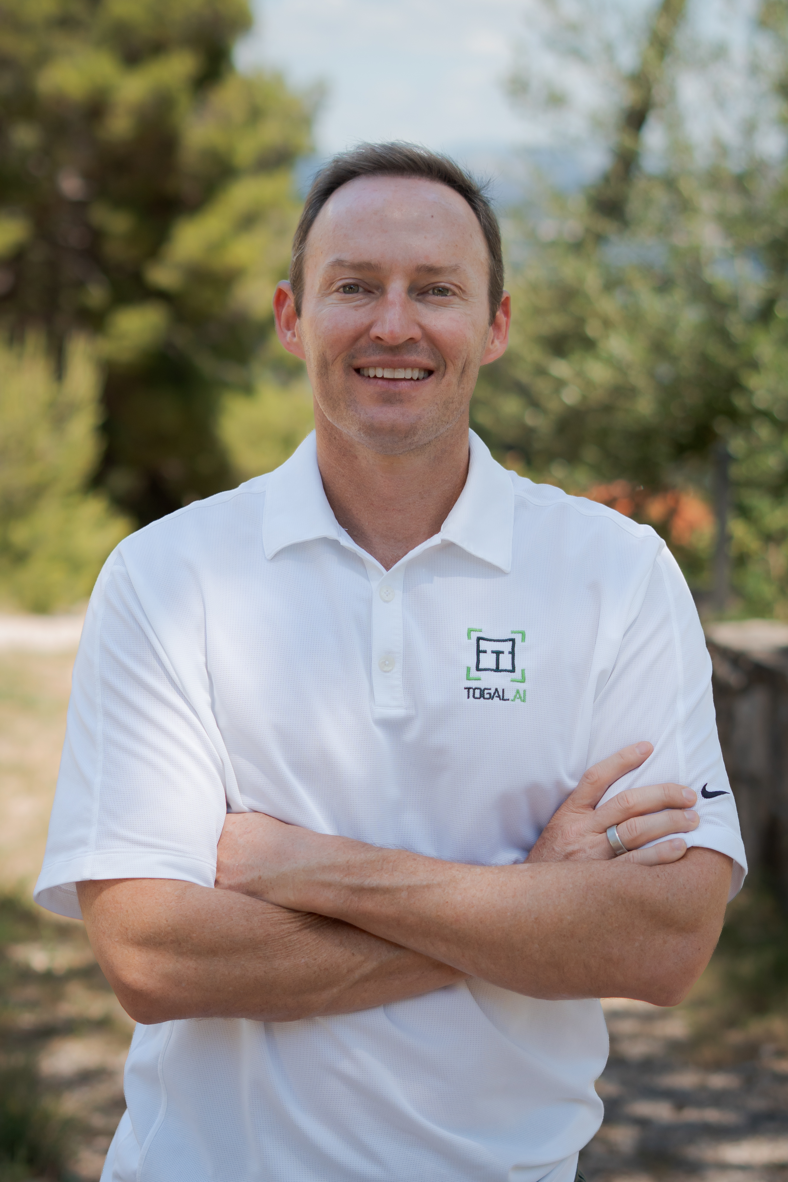 Smiling professional in white Togal.AI polo shirt standing outdoors Headshot