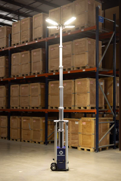 Telescoping mobile light tower in warehouse with stacked wooden shipping crates