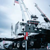 White mobile crane with extended boom and American flag on industrial site