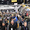 Crowded industrial trade show with attendees walking between customer service and registration areas