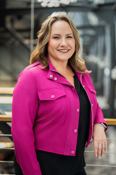 Professional woman in pink jacket smiling confidently in office setting