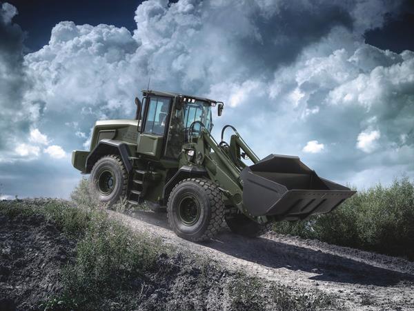 Military green wheel loader climbing rocky terrain under dramatic cloudy sky