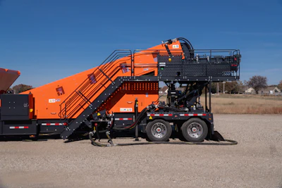 Orange and black industrial waste compactor truck with extended hydraulic lift system parked in outdoor lot