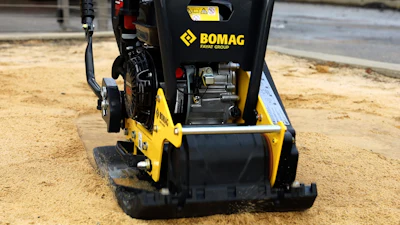 Yellow and black Bomag compactor on sandy construction site