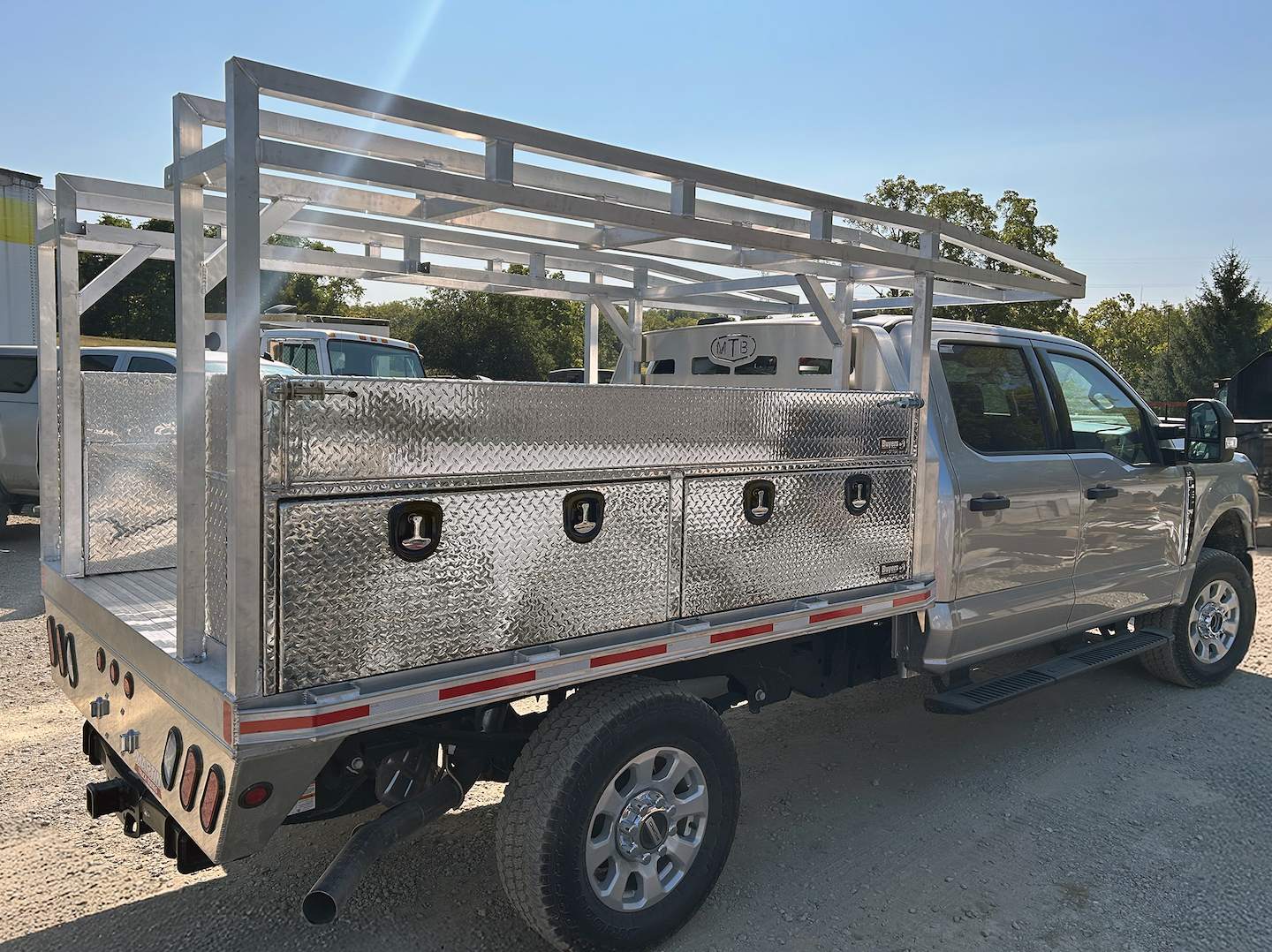 Silver pickup truck with aluminum utility bed and overhead rack in parking lot