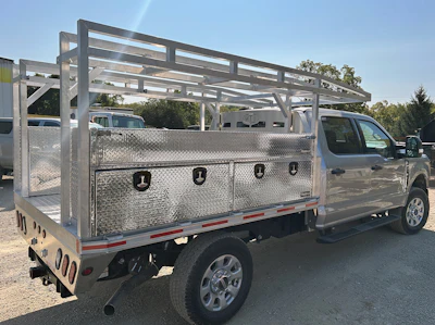 Silver pickup truck with aluminum utility bed and overhead rack in parking lot