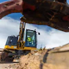 Yellow excavator working on dirt terrain with construction equipment in background