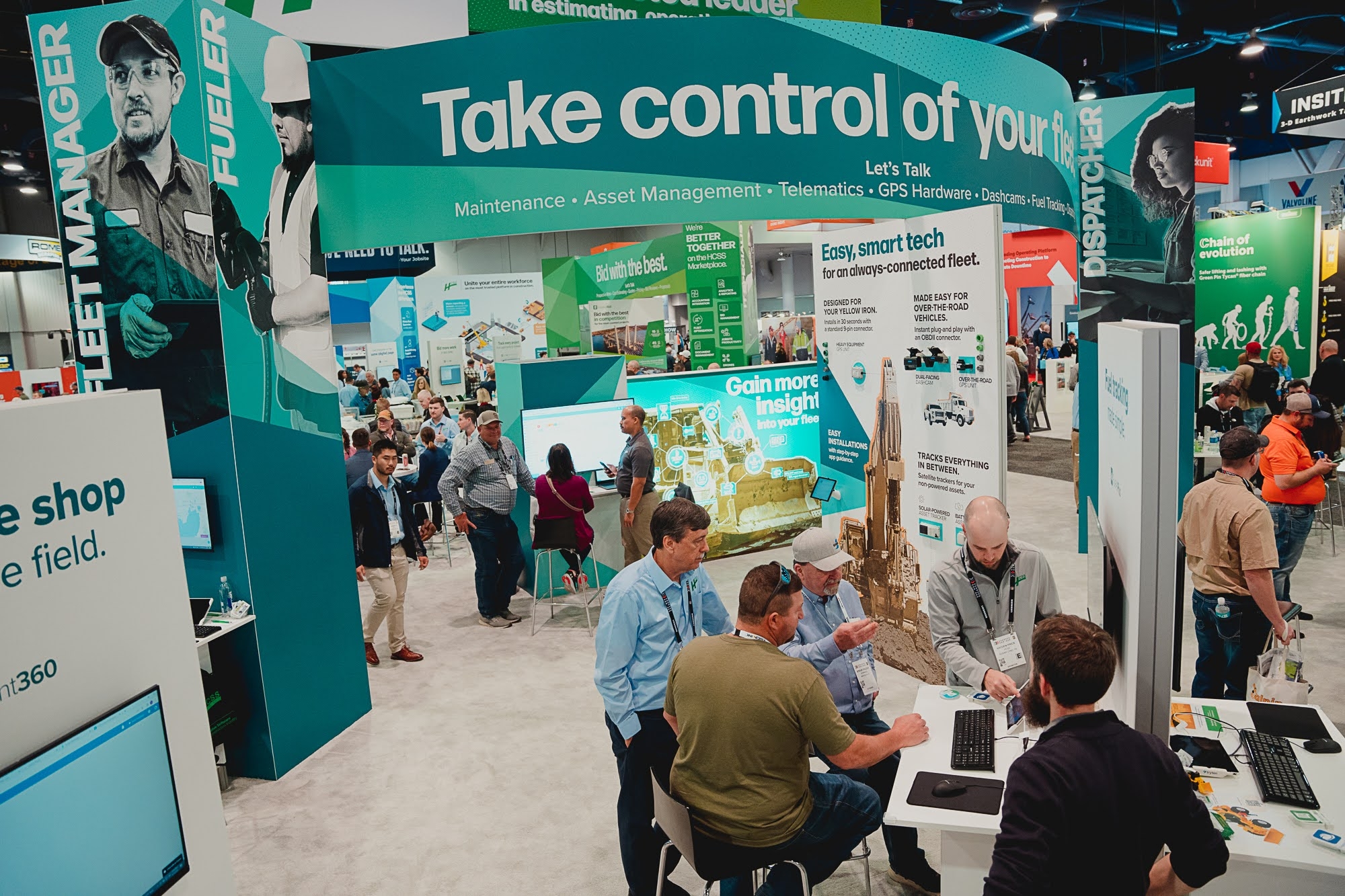 Trade show booth showcasing fleet management technology with attendees and displays