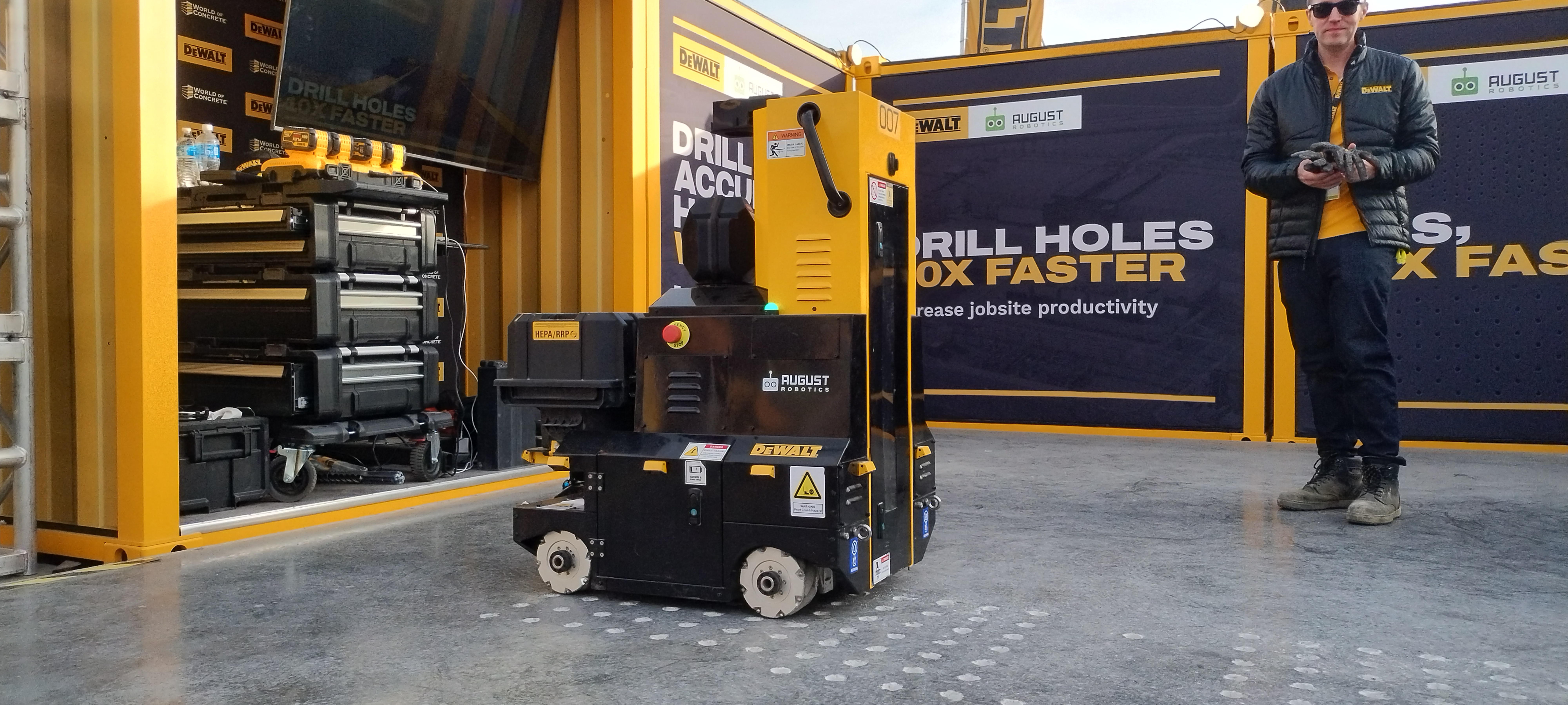 Yellow industrial drill machine with marketing banners in workshop setting