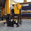 Yellow industrial drill machine with marketing banners in workshop setting