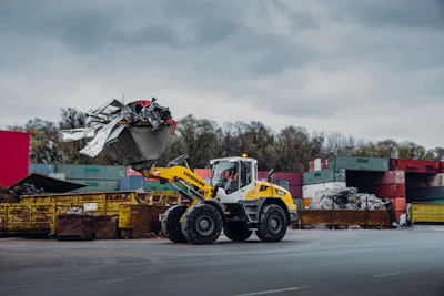 Yellow Liebherr wheel loader moving scrap metal at industrial recycling facility